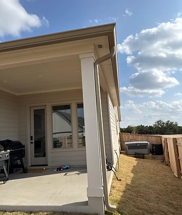 New color-matched downspout running down a covered patio column, carrying roof runoff away from the slab