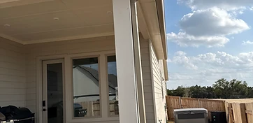 New color-matched downspout running down a covered patio column, carrying roof runoff away from the slab