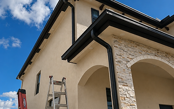 Black seamless gutters custom-formed on a two-story stucco home