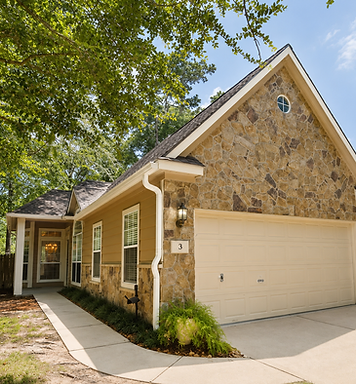 Complete seamless gutter system installed on a stone Woodlands home under mature trees, protecting the foundation from storm runoff
