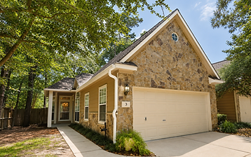 Complete gutter system installed on a stone Woodlands home under mature trees
