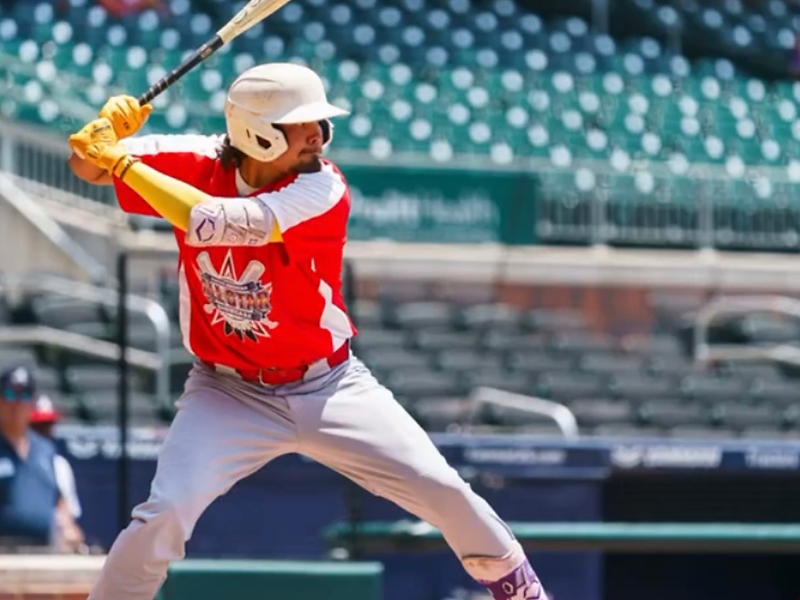 PHC coach mid-swing in red uniform at the Native American All-Star Showcase