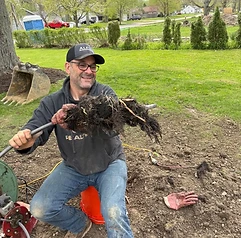 Alfieri Brothers crew member in an ALFIERI hat holding tree roots pulled from a sewer line