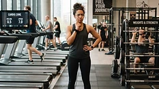 A person looking puzzled choosing between a treadmill and weights in a gym