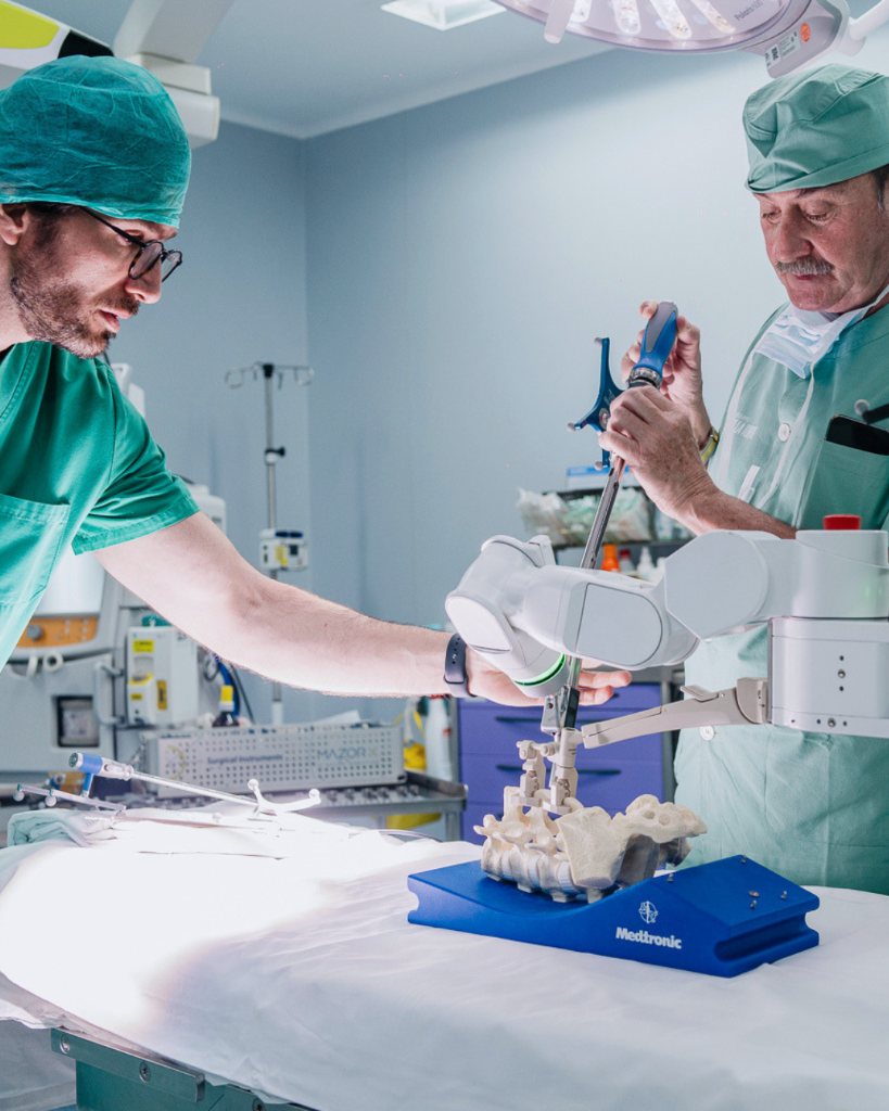 Equipo médico trabajando con asistencia robótica sobre un modelo de columna