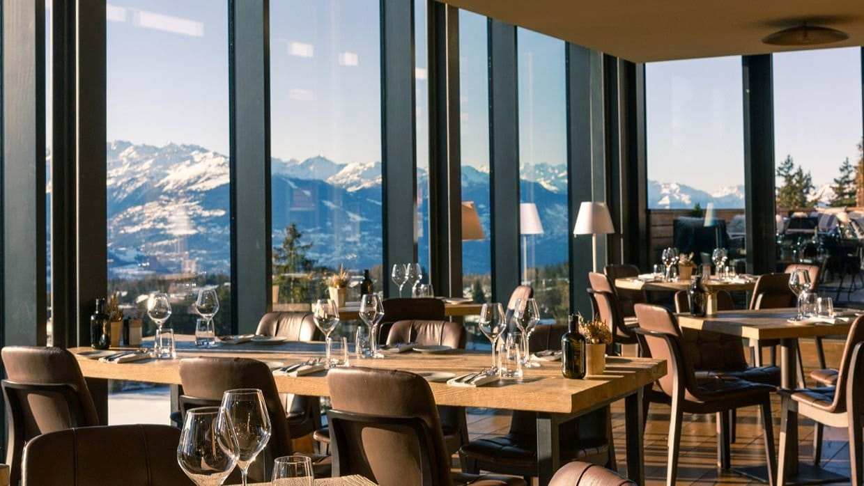 Restaurant at Crans Ambassador with floor-to-ceiling windows overlooking the snow-capped mountains