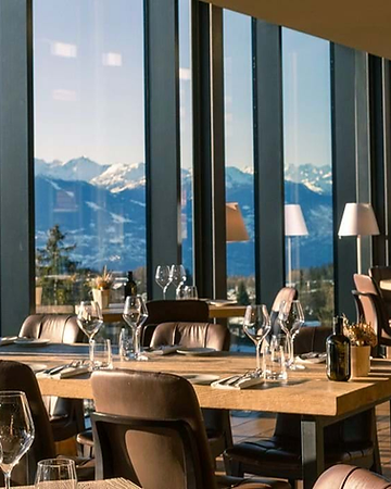 Restaurant at Crans Ambassador with floor-to-ceiling windows overlooking the snow-capped mountains