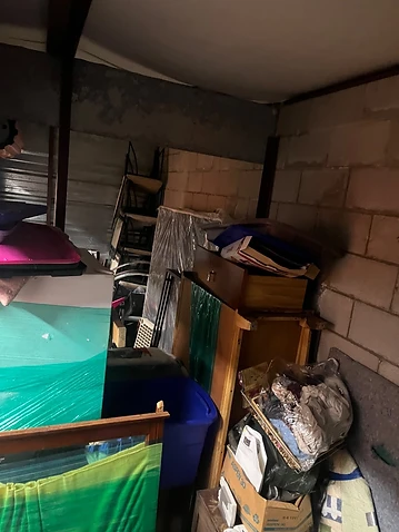 Packed storage unit filled with furniture, boxes and appliances before cleanout in Merrionette Park