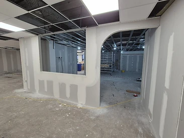 Drywall partition with a window cutout and an arched doorway during installation