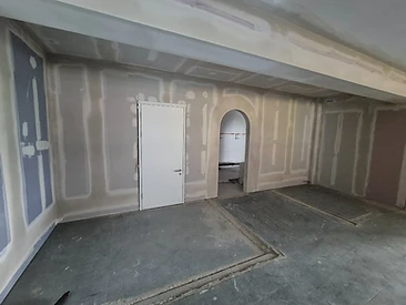 Finished plasterboard partition with a white door and an arched opening