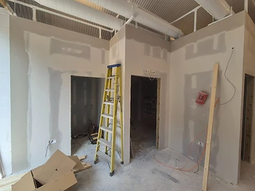 Plasterboarded partition wall with jointed seams and a ladder in front of a doorway opening