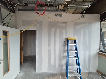 Taped and jointed partition wall with an open doorway and exposed ceiling cable trays