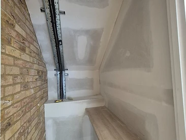 Small sanded workspace alcove formed by a partition wall under a sloped ceiling