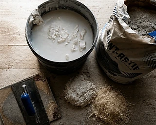 Lime plaster mix, fibre reinforcement and trowel on a workshop bench