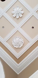 A decorative ceiling divided into a grid of diamonds with two white plaster rosettes