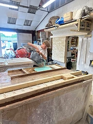 A craftsman pouring liquid silicone rubber over a master to form a casting mould