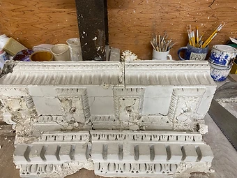 A heavily cracked and fragmented section of the original decorative plaster cornice resting on a workbench