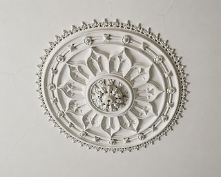 Aged decorative plaster ceiling rose with hairline cracks radiating from the ornament
