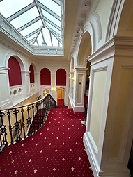 The principal hallway with ornate plaster work beneath a glass skylight