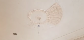 The central ceiling medallion half-adorned during installation, with plaster petals being fixed around the perimeter