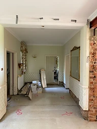 The reception hall at the outset of the works, with exposed brickwork, a structural steel beam and building materials stored on the bare concrete floor