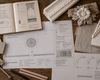 Architectural drawings, survey plans and plaster samples laid out on a workbench