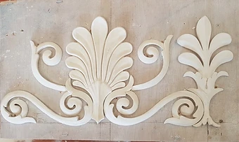 A newly cast white plaster acanthus and palmette enrichment resting on a timber mounting board