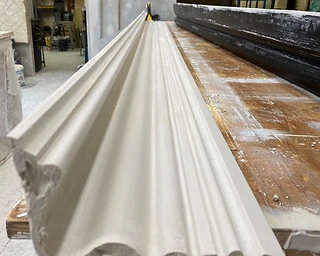 Freshly cast plaster cornice resting on a workshop bench