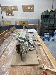 A damaged original cornice fragment held in place with a strap on the workbench