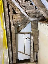 Modern insulation foam and protective sheeting packed between aged elm timbers during earlier repairs