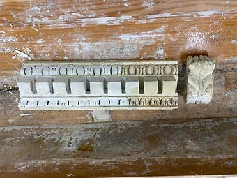 An original cornice fragment being cleaned, with later paint layers removed
