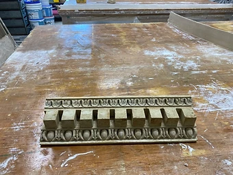 A cleaned cast section of cornice moulding with dentils and an egg-and-dart band