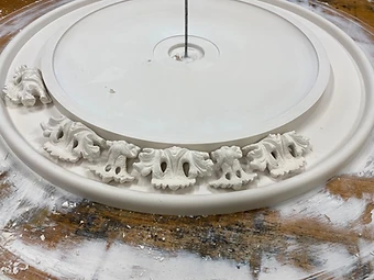 A bespoke plaster ceiling rose in assembly, with individual leaf ornaments set around the inner ring