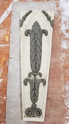 A bespoke Gothic-arched plaster panel with clay acanthus modelling laid flat on the bench
