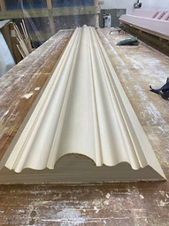 A finished length of run plaster cornice resting on the workbench