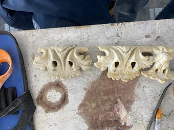Two cast plaster acanthus-leaf enrichments placed side by side on a work table