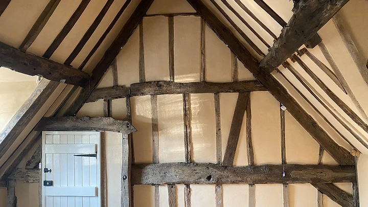 The vaulted bedroom during the reinstatement works, with exposed timber framing and lime-plastered walls taking shape around the doorway