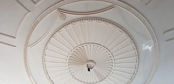 Close-up of the completed circular neoclassical plaster ceiling rose with radiating fluted petals