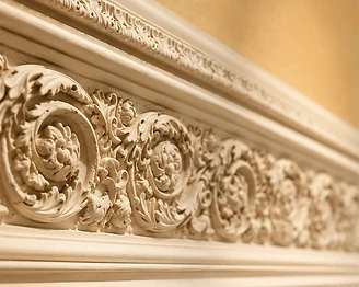 Close-up of an ornate classical plaster cornice with rosette medallions and acanthus foliage
