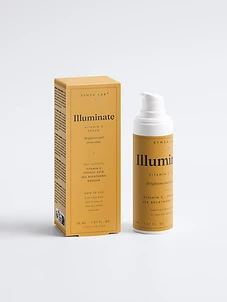 Illuminate vitamin C serum bottle and carton on mustard yellow backdrop