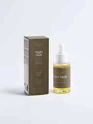 Night Shift bakuchiol face oil bottle and carton on bronze backdrop in evening light