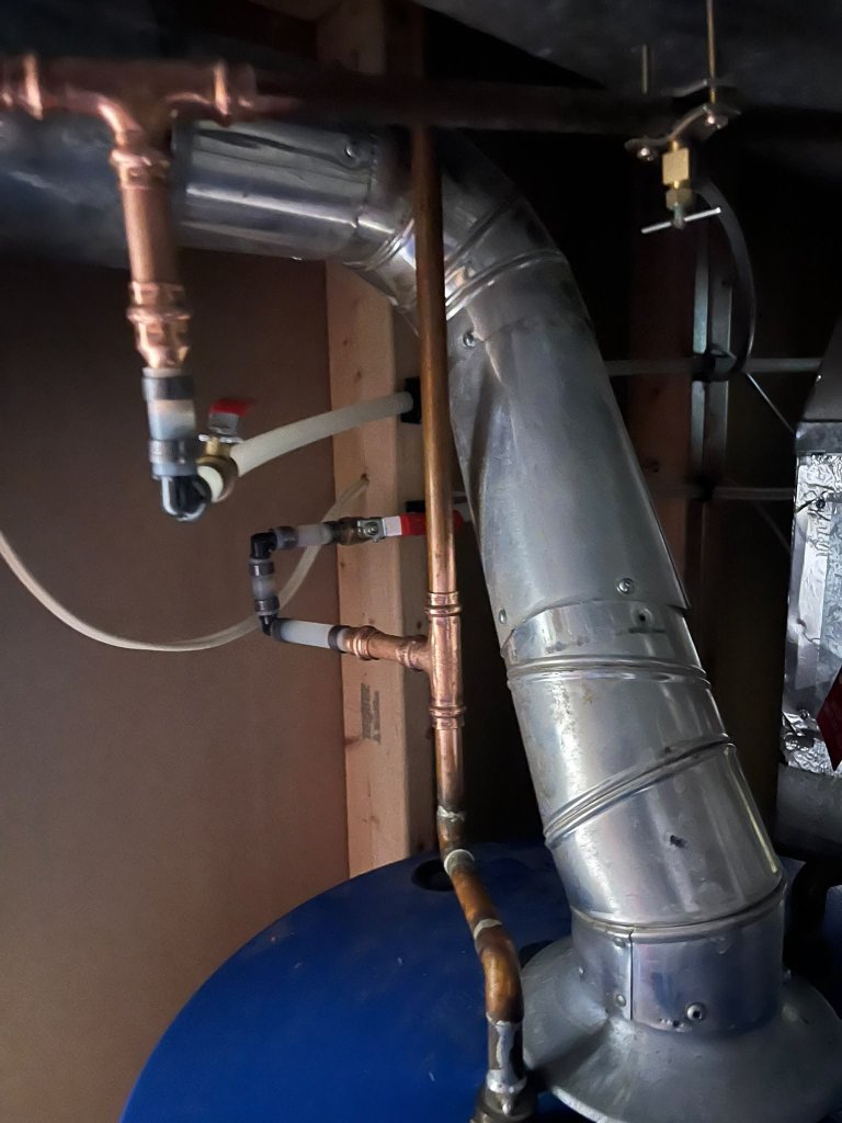 Drain connection and flue routing for a water heater installation.