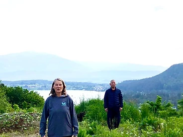Two people standing by a lake with mountains in the distance