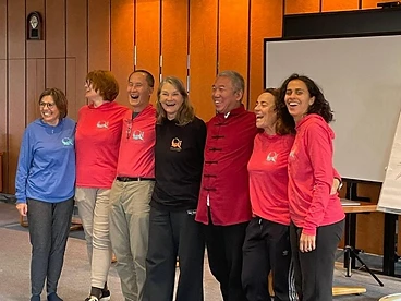 Group of coaches smiling in front of a wooden slat wall