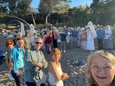 Large group gathered on a pebble beach at sunset