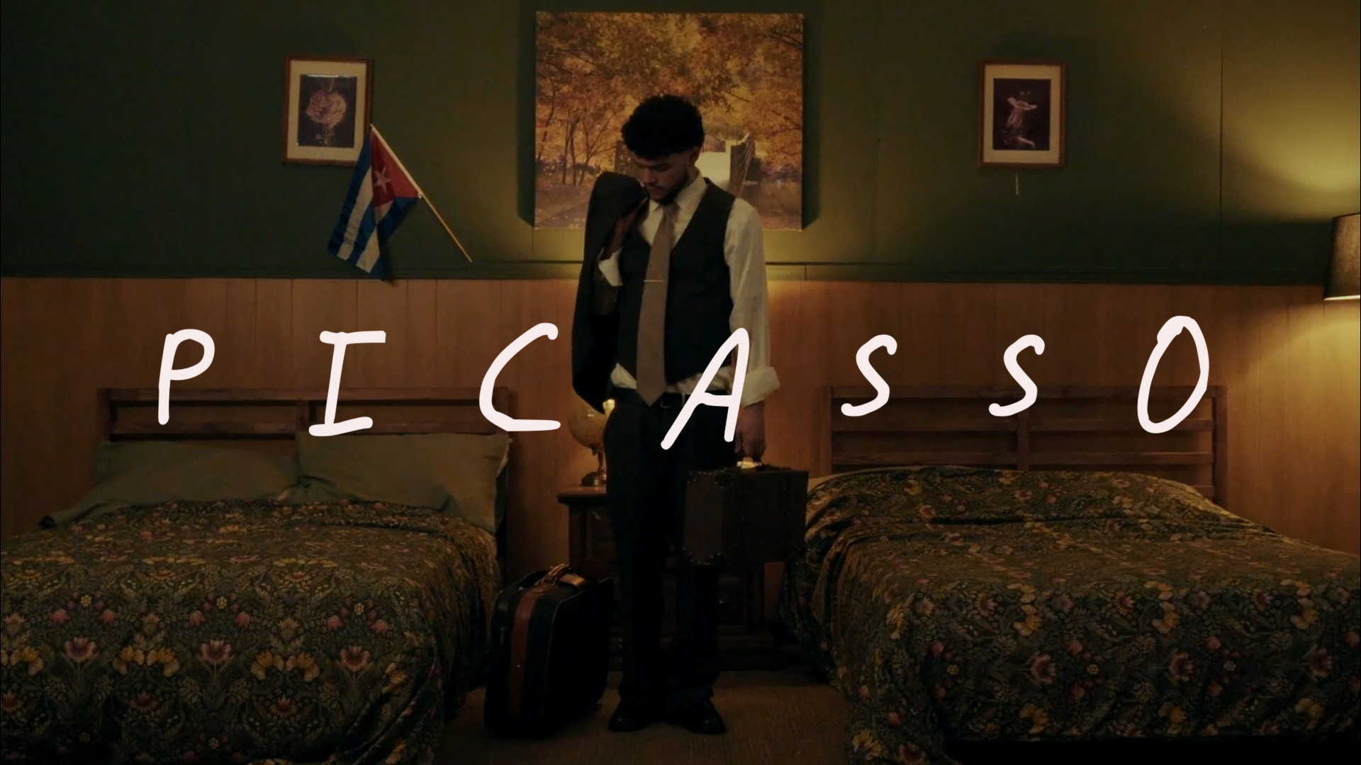 Yuma de pie entre dos camas en una habitación vintage con la palabra PICASSO en primer plano