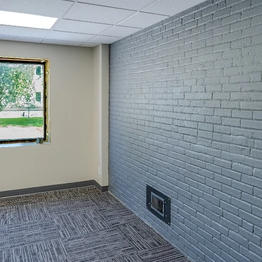 Corner office suite with brick accent wall and natural light
