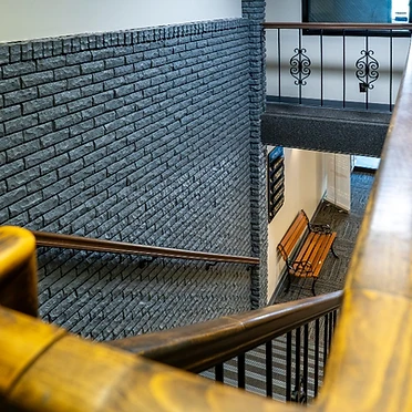 Staircase with charcoal brick wall and wood handrail