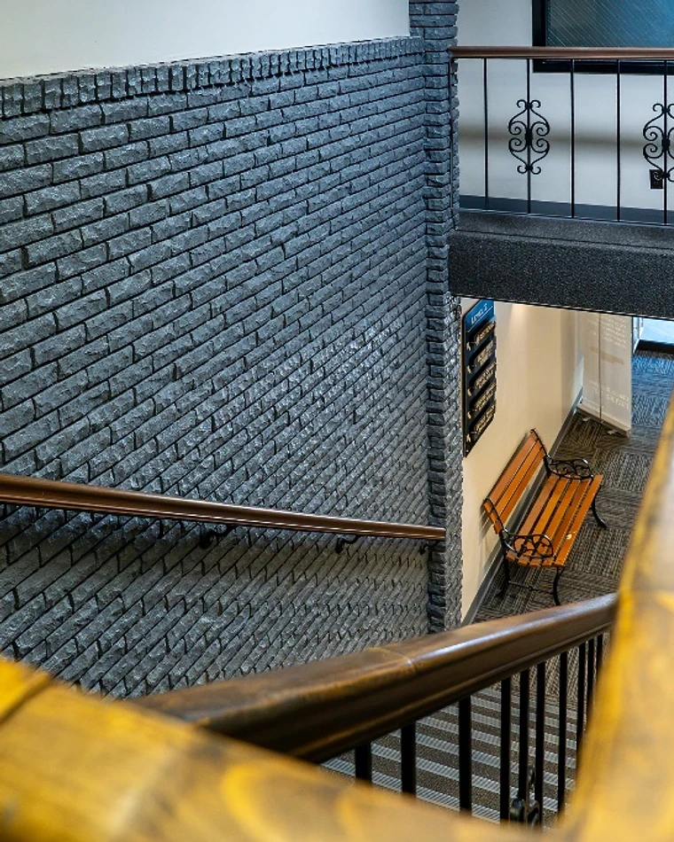 Staircase with charcoal brick wall and wood handrail