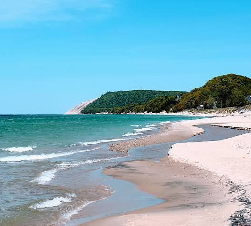 Beach at the base of a forested dune near Empire, Michigan with turquoise water and sandy shoreline